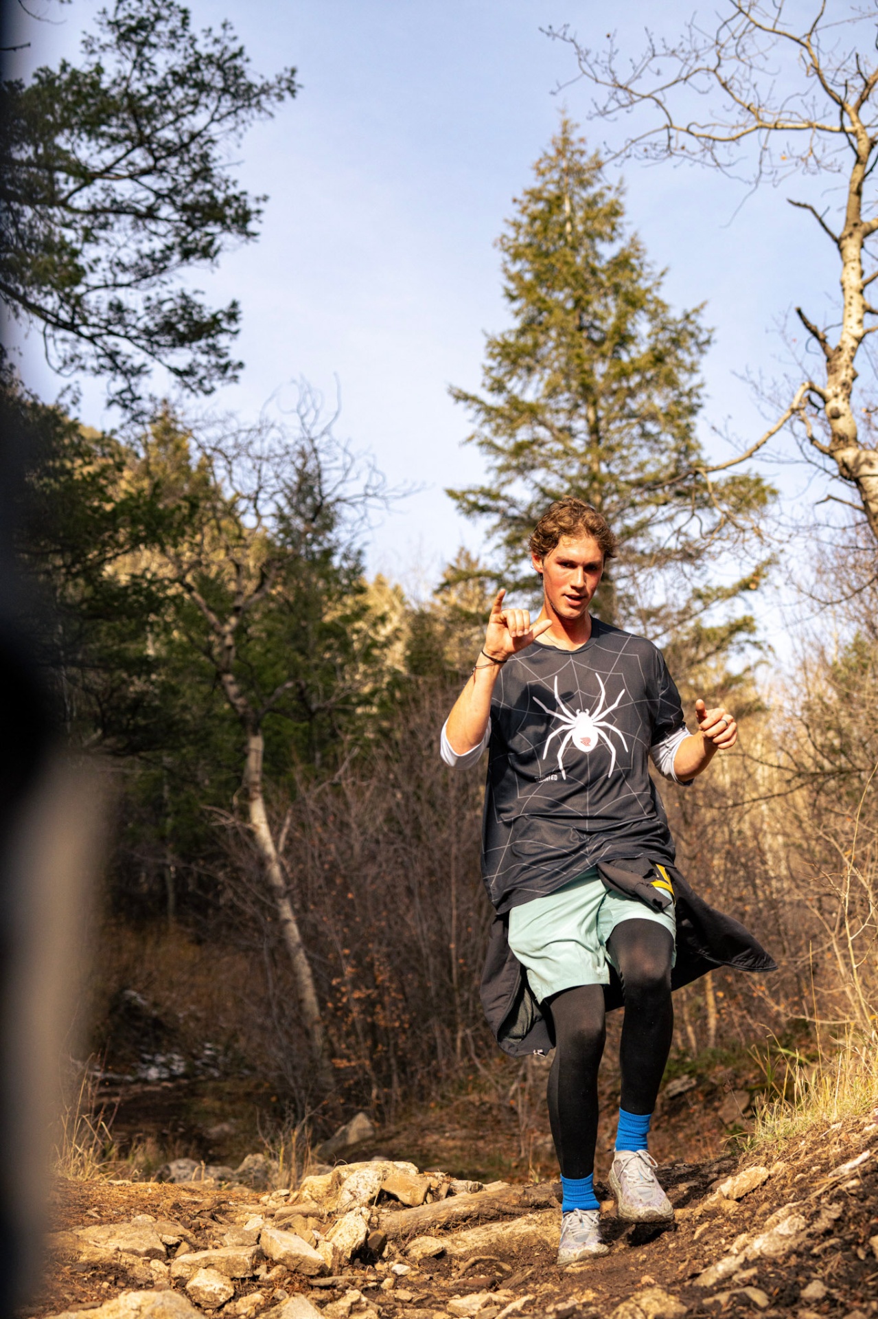 Runner in a spider-web shirt on a forested trail