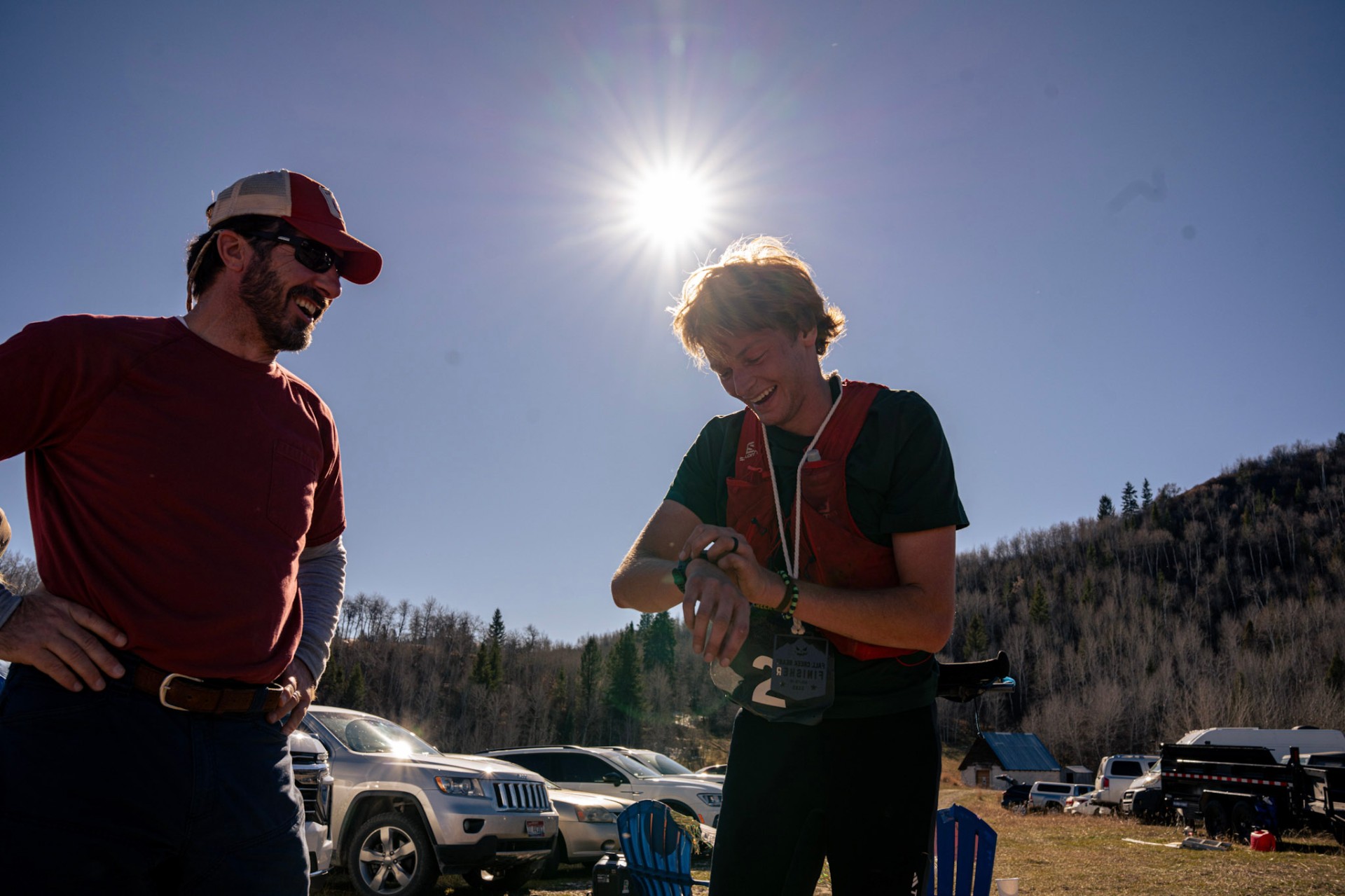 Finisher laughing with a volunteer under a bright sunburst