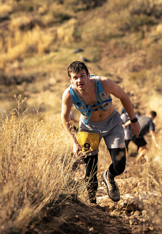 Runner with bib 9 climbing a steep golden hillside