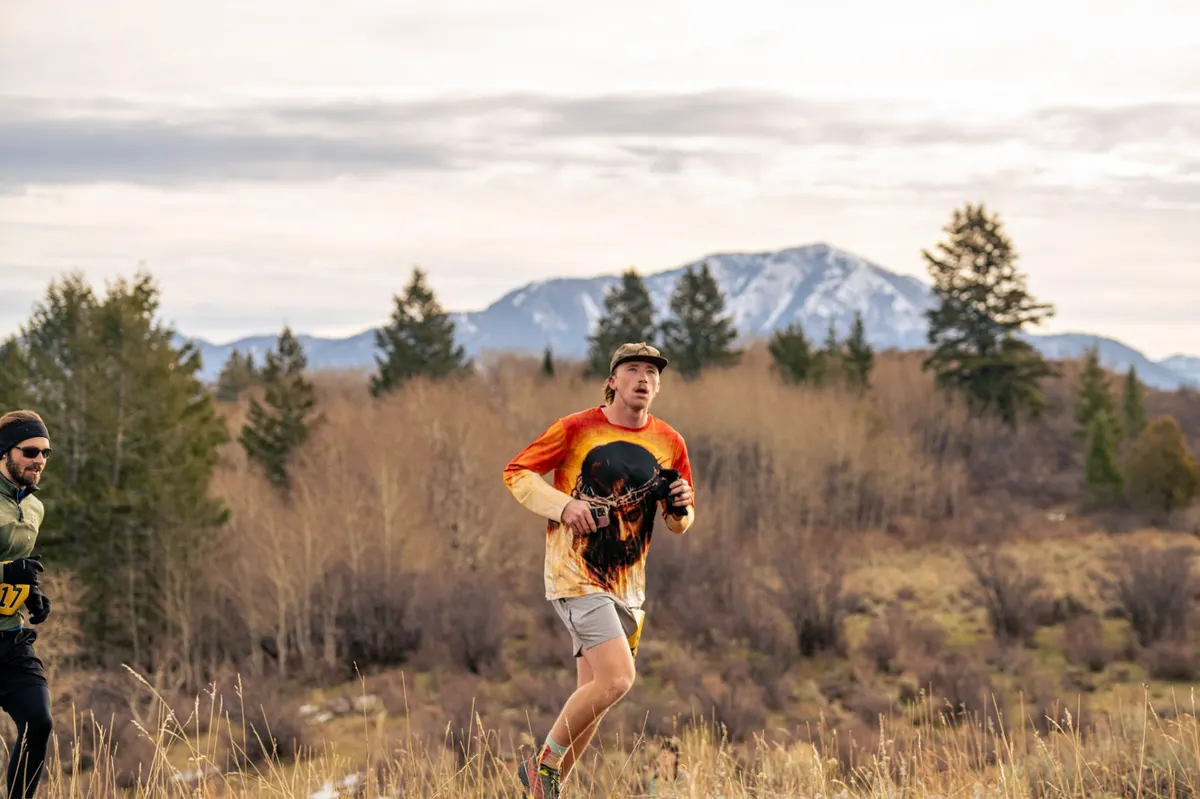Runner in a vivid orange shirt against the Tetons