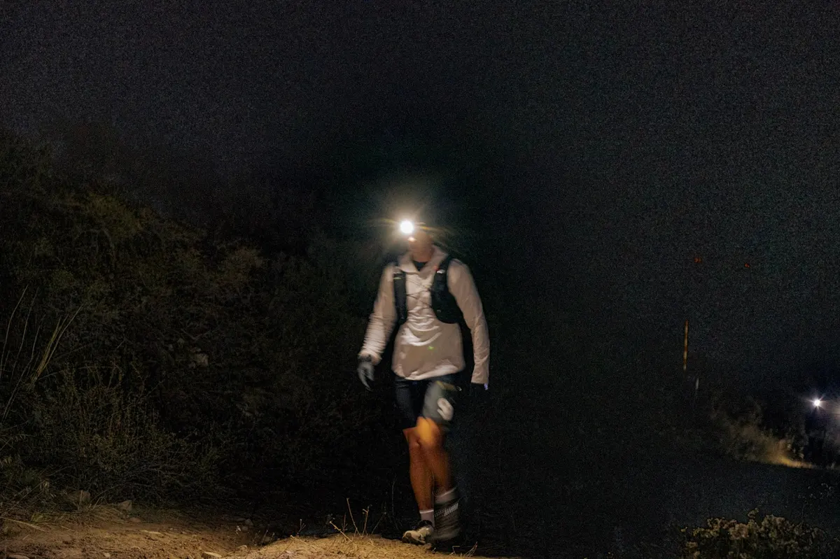 Lone runner climbing in the dark with a single headlamp