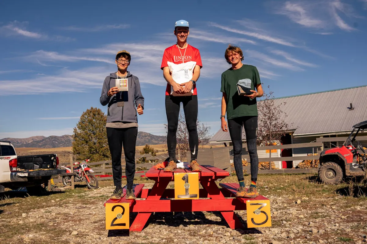 Top three finishers on the red podium with mountain backdrop