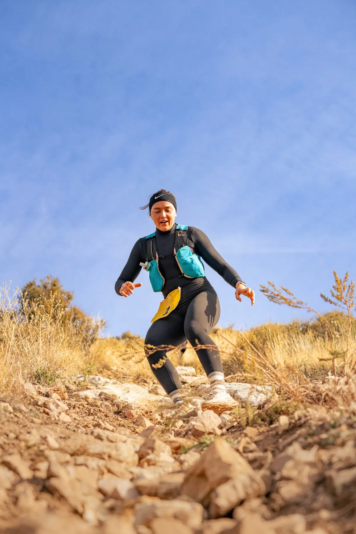 Runner descending a rocky trail under blue sky