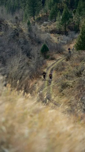 Two runners moving up a hillside singletrack