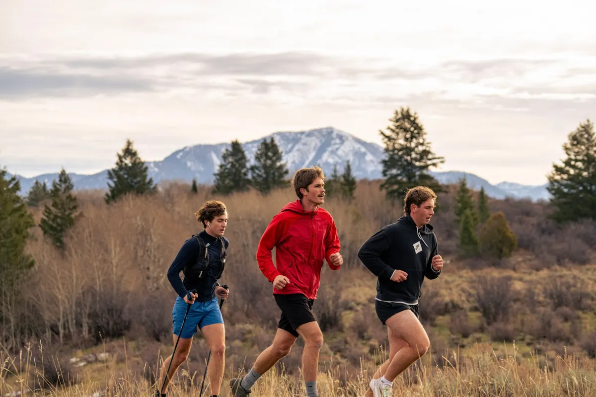 Three runners side by side crossing an open meadow
